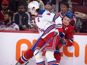 Montreal Canadiens centre Nick Suzuki (14) grimaces as he is hit by New York Rangers defenseman Jacob Trouba (8) during NHL action in Montreal, on Jan. 5, 2023.