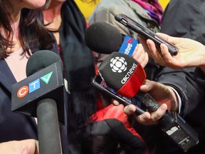 Microphones are visible during a media scrum.