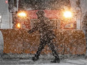 A pedestrian can hardly be seen with the falling snow as he passes in front of a snowplow on René-Lévesque Blvd. on Dec. 16, 2022.