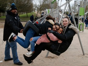 Parents Trevor Daly (left) and Rebecca Nicholson (right) pose for a photo with their daughter Shania Daly, 5, (2nd right) and goddaughter Trinity, 13, (2nd left) on a playground swing in Victoria Park on March 6, 2021 in London, England.  A study compared this and other innovative parks in the United Kingdom to smaller parks in the United States and found that they encourage much more activity.