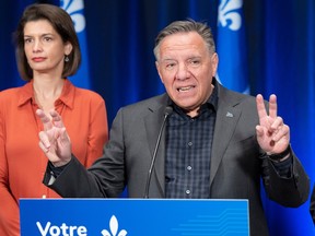 Premier François Legault speaks to the media as Deputy Premier Geneviève Guilbault looks on after the CAQ caucus meeting on Friday.