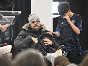 Ayman Derbali, injured victim of the 2017 mosque shooting, speaks of the ordeal as his son Ayoub cries while holding the microphone during a ceremony, Sunday, Jan. 29, 2023, at the mosque in Quebec City. An emotional ceremony took place Sunday marking the sixth anniversary of the Quebec City mosque shooting, held for the first time in the same room where many of the victims were killed.