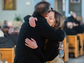 People embrace during a mass in S-Roch-de-l'Achigan on Sunday, Jan. 15, 2023, in memory of the victims of a propane explosion just outside the town on Thursday.