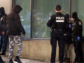 Montreal Police officers talk with homeless people outside the shelter in the Hotel Place Dupuis in 2021.