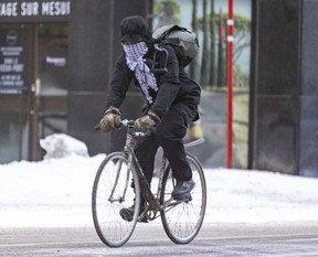 A bike messenger rides into the wind on a bitterly cold and windy day in Montreal on Friday, Feb. 3, 2023.
