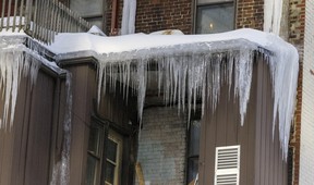 Des glaçons pendent d'un toit à l'arrière d'un immeuble du centre-ville par une journée extrêmement froide et venteuse à Montréal le vendredi 3 février 2023.