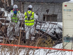 Inspectors look over the scene of a burned down home in St-Jacques, where at least four bodies were found on Feb. 9, 2023