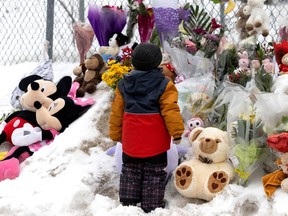 A young boy visits a shrine outside his daycare centre, the site of a fatal bus crash, in Laval on Thursday, Feb. 9, 2023.