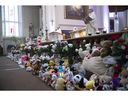 Flowers and teddy bears line the front of Laval's Eglise Ste-Rose-de-Lima church on Friday Feb. 10, 2023 during a community mass in memory of the two children who were killed and injured in Wednesday's bus crash.