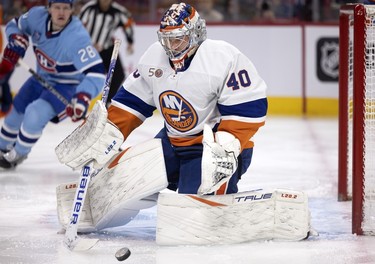 Montreal Canadiens centre Christian Dvorak (28) watches as New York Islanders goaltender Semyon Varlamov (40) sweeps the puck away during first-period action in Montreal on Saturday, Feb. 11, 2023.