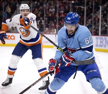 Montreal Canadiens right wing Alex Belzile (60) grimaces as New York Islanders defenceman Scott Mayfield (24) jerks his trapped stick back and forth during first-period action in Montreal, on Saturday, Feb. 11, 2023.