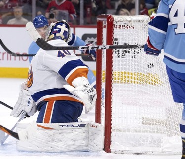 Montreal Canadiens centre Nick Suzuki (14) watches as the pack sails past New York Islanders goaltender Semyon Varlamov (40) during first-period action in Montreal on Saturday, Feb. 11, 2023.