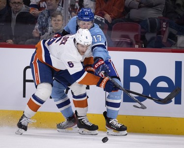 Montreal Canadiens right wing Josh Anderson (17) and New York Islanders defenceman Ryan Pulock (6) spar for control of the puck during first-period action in Montreal on Saturday, Feb. 11, 2023.