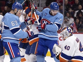 Canadiens' Evgenii Dadonov (63) and centre Kirby Dach (77) look down to see New York Islanders goaltender Semyon Varlamov has made a glove save during first-period action in Montreal on Saturday, Feb. 11, 2023.