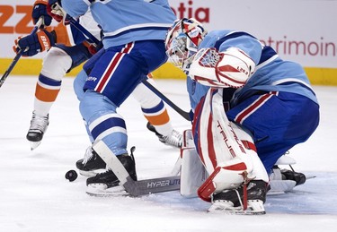 Montreal Canadiens goaltender Sam Montembeault (35) tries to recover a puck from between Montreal Canadiens defenceman David Savard's (58) skates during 2nd-period action against the New York Islanders in Montreal on Saturday, Feb. 11, 2023.