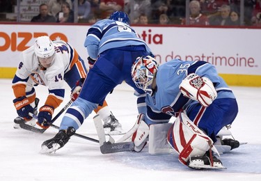 New York Islanders centre Bo Horvat (14) and Montreal Canadiens goaltender Sam Montembeault (35) struggle for a loose puck that sits between Montreal Canadiens defenceman David Savard's (58) skates during 2nd-period action in Montreal on Saturday, Feb. 11, 2023.