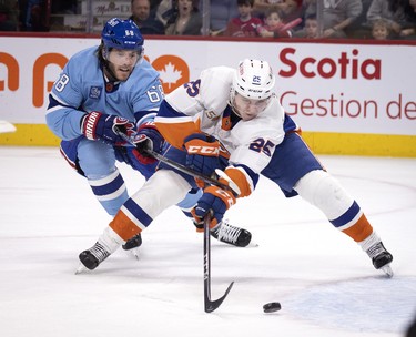 Montreal Canadiens left wing Mike Hoffman (68) holds New York Islanders defenceman Sebastian Aho (25) during overtime  action in Montreal on Saturday, Feb. 11, 2023.