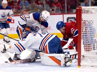 Edmonton Oilers goaltender Stuart Skinner tries to cover up as Canadiens' Alex Belzile (60) falls next to him and Oilers defenceman Brett Kulak (27) tries to block Belzile during first period NHL action in Montreal on Sunday, Feb. 12, 2023. Belize scored his first career goal with the Habs seconds later.