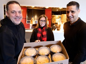 The staff at Del Frisco's Restaurant prepared 25 lunches of chicken pasta for students at St. Charles Elementary School in Pierrefonds on Tuesday. Principal Lisa Baylis accepts the food from Del Frisco's co-owner John Thanopoulos, left, and Terry Konstas.