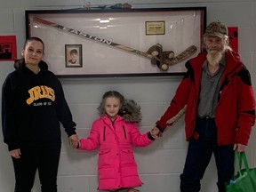 Lynne Baudouy, Guy Gaudet, and daughter Victoria-Angèlle, next to display case at John Rennie High School. Case is in tribute to Lucas Gaudet, the teen who died  Feb. 10, 2022, two days after being stabbed during an altercation near St. Thomas High School in Pointe-Claire.