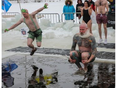 Montreal city councillor Sterling Downey (right) and others jump into the frigid waters of the Lachine Canal on Saturday, Feb. 18, 2023, as they took part in the 15th edition of the Polar Bear Challenge.