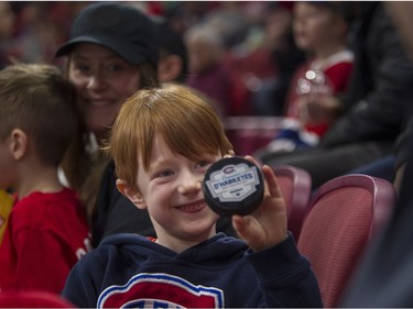 Charles Laflamme shows his dad a puck he got from a Canadiens player at the Canadiens skills competition at the Bell Centre in Montreal on Sunday, Feb. 19, 2023.