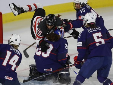 Sarah Nurse of team Canada goes over team USA goalie Nicole Hensley, during first period action in the final game of the women's hockey Rivalry Series in Laval on Wednesday Feb. 22, 2023.