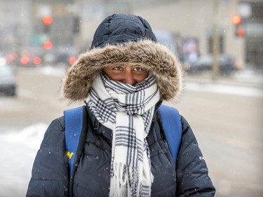 Zoya Masood uses her hood and a big scarf to battle blowing snow on a cold, windy day in Montreal Thursday Feb. 23, 2023.