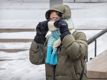 A pedestrian pulls her scarf up onto her face against blowing snow on a cold, windy day in Montreal Thursday Feb. 23, 2023.