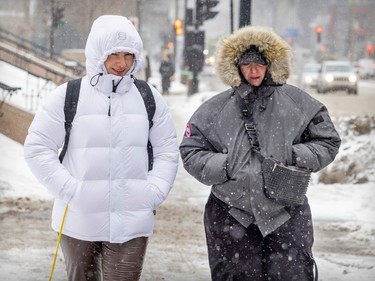 Sisters Rita, left, and Rime Sbai had their hoods on tight against blowing snow on a cold, windy day in Montreal Thursday Feb. 23, 2023. Rime Sbai was experiencing winter for the first time in her life, visiting her sister from Morocco.