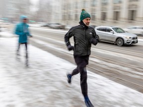 Runners take on blowing snow during a cold, windy day on Réne-Lévesque Blvd., Feb. 23, 2023.