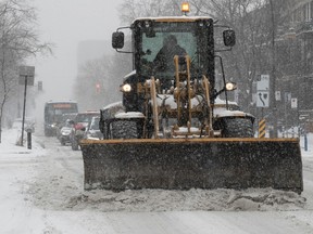 A snowplow holds back commuters on their way towards downtown on St-Denis Street on Tuesday Feb. 28, 2023 during morning snowfall.