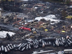 Workers comb through debris after a train derailed Saturday, July 9, 2013 causing explosions of railway cars carrying crude oil in Lac-Megantic, Quebec. The federal government is moving to acquire land so that it can build a rail bypass in Lac-Megantic, Que., nearly 10 years after a downtown freight train derailment killed 47 people.