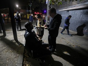 Interviewers speak with a man during a count of unhoused people in Montreal on Oct. 11, 2022.