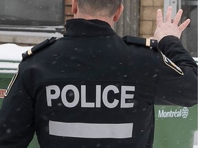 a montreal police officer seen from behind with his hand extended upward