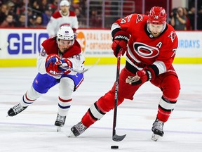 Jaccob Slavin #74 of the Carolina Hurricanes skates with the puck while Rafael Harvey-Pinard #49 of the Montreal Canadiens tries for it during the first period of the game at PNC Arena on February 16, 2023 in Raleigh, North Carolina.