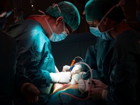 Two doctors stand over a patient at an operating table