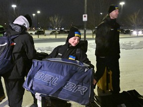 Ukrainian peewee hockey player Zahar Kovalenko carries his bag as head coach Evgheniy Pysarenko walks behind as they arrive, Wed., Feb. 1, 2023, at the Videotron Centre in Quebec City. The Ukraine team will compete at the Quebec International Peewee Hockey Tournament.