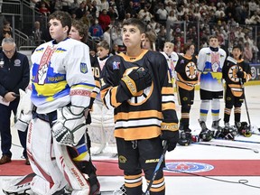 Team Ukraine Select and Boston Junior Bruins peewee teams stand together during the national anthems before their game, Saturday, Feb. 11, 2023, at Quebec's international peewee tournament in Quebec City.