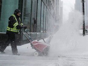 Denis Rodin uses small snowblower to clear front entrance of downtown building in February.