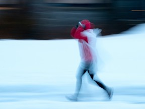 A runner tries to keep dry in cold evening rain in March 2020.