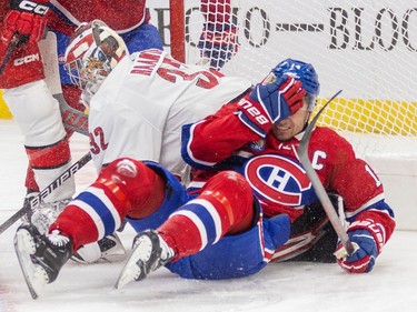 Canadiens' Nick Suzuki grabs his head after crashing face-first into the crossbar next to Carolina Hurricanes goalie Antti Raanta during first period of National Hockey League game in Montreal Tuesday March 7, 2023.
