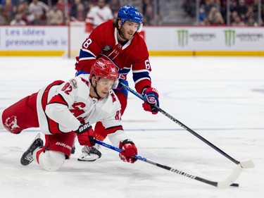 Carolina Hurricanes' Jesperi Kotkaniemi falls while making a pass under pressure from Montreal Canadiens Mike Hoffman during second period of National Hockey League game in Montreal Tuesday March 7, 2023.