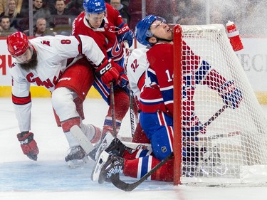 Canadiens' Nick Suzuki hits his head on the crossbar as he crashes into Carolina Hurricanes net  during first period of National Hockey League game in Montreal Tuesday March 7, 2023.  Hurricanes' Brent Burns and Canadiens' Jesse Ylonen battle for loose puck in background.