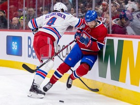 Canadiens' Chris Tierney is driven into the end boards by New York Rangers' Braden Schneider during the first period of a National Hockey League game in Montreal Thursday March 9, 2023.