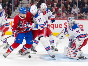 Montreal Canadiens' Alex Belzile competes for a loose puck with New York Rangers' Niko Mikkola as Adam Fox, rear, backs up goalie Igor Shesterkin during the first period of a National Hockey League game in Montreal Thursday March 9, 2023.