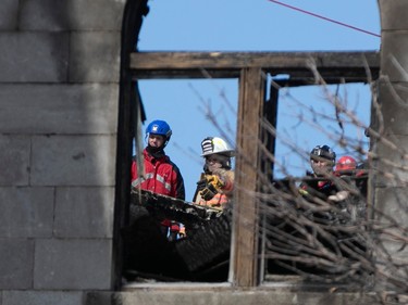 Montreal firefighters and members of a demolition crew consult Wednesday March 22, 2023 at the scene of last week's Old Montreal fire.