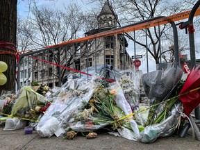Flowers lay near the scene of the Old Montreal fire March 28, 2023. The bodies of the seven missing people have been retrieved from the building in the background and the investigation into the cause of the fire will begin.