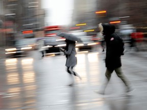 Pedestrians dash across Sherbrooke St. as a cold rain falls on Montreal in this April 2019 file photo.
