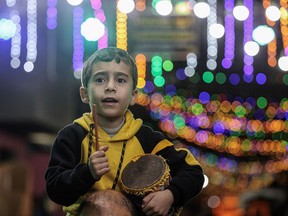 A Palestinian child plays music during a festive event to celebrate Ramadan, two days before it starts, in Khan Yunis town in the southern Gaza Strip.